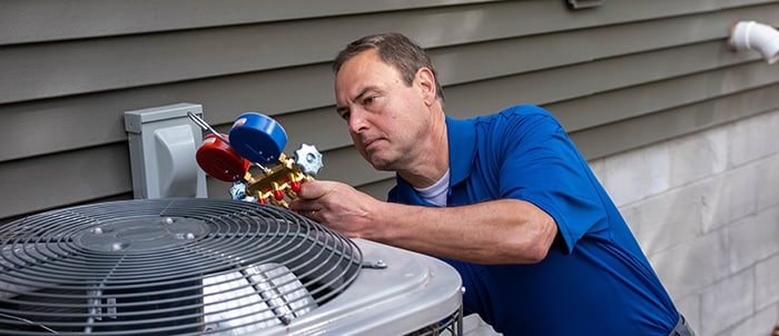 worker looking at HVAC unit with gauges